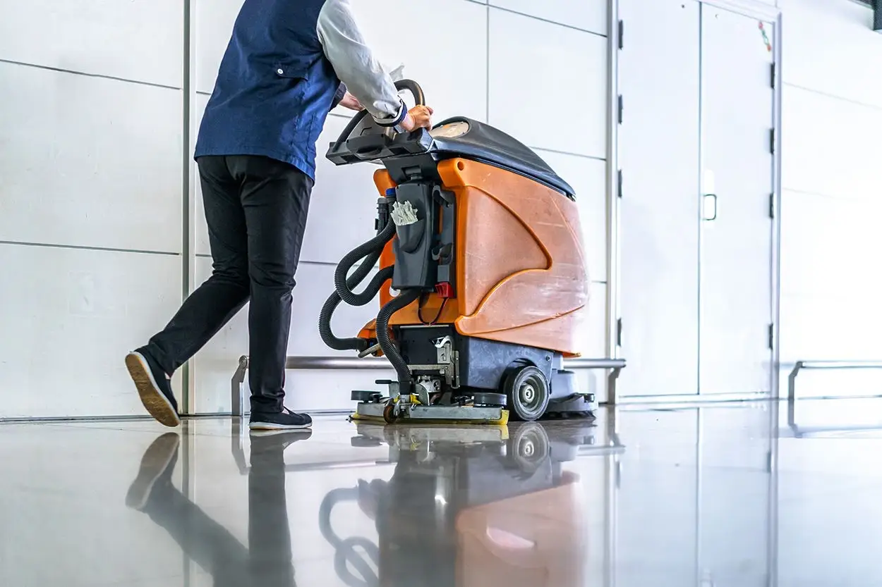 A person is operating a commercial floor cleaning machine inside a building.